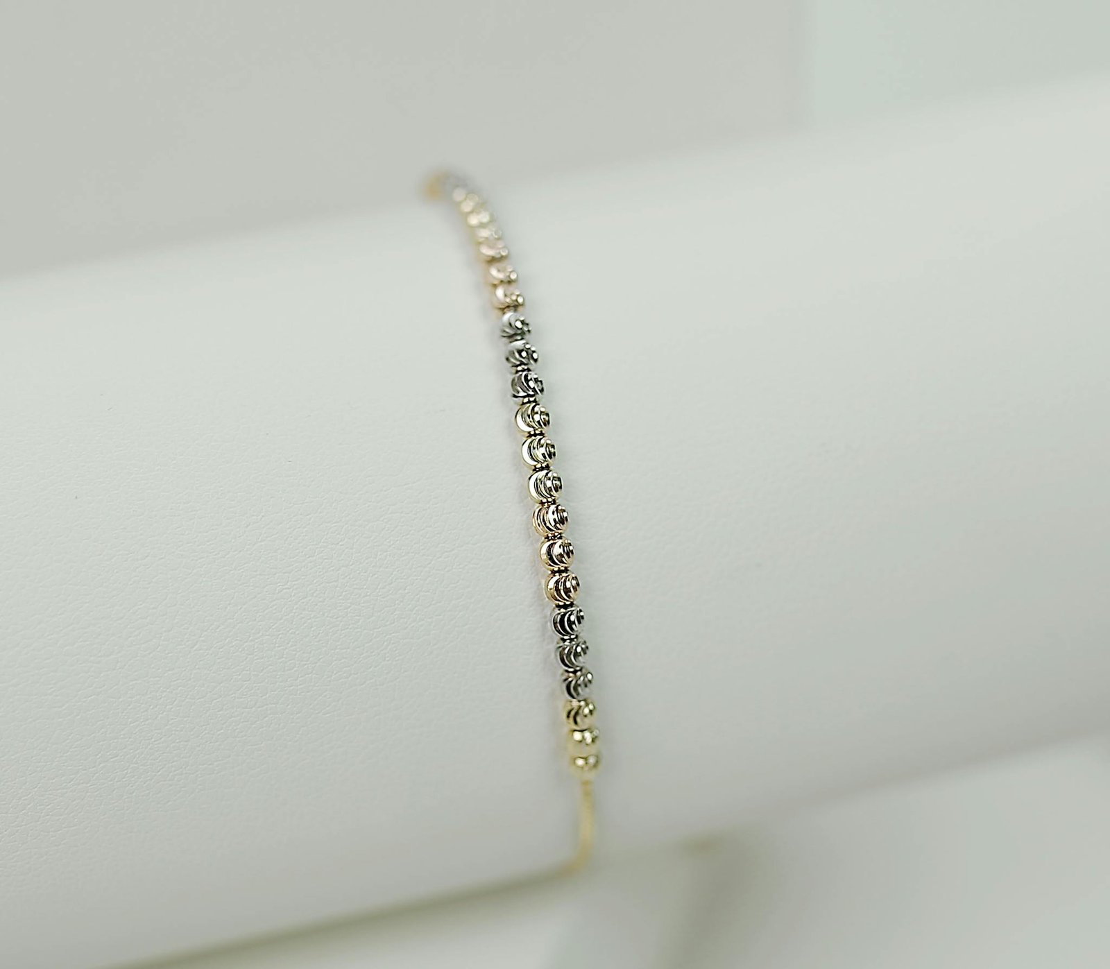 Close-up of a delicate gold and silver bracelet on a white background.